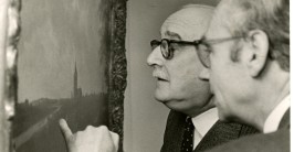 Foto: Zwei Männer analysieren ein Gemälde an der Wand