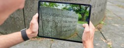 Jemand hält ein Tablet auf dem ein Bild angezeigt wird mit Erinnerungen an Konzentrationslager
