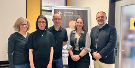 Foto von f&uuml;nf Personen vor einem Aufsteller