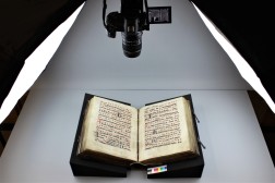 Auf Schaumstoffkeilen liegendes Buch, Beleuchtung von den Seiten, darüber ein Stativ mit Fotokamera