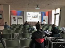 Teilnehmende einer Tagung in Stuhlreihen vor einer Leinwand mit Präsentation