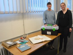 Zwei Personen stehe hinter einem Tisch und haben ihre Hände auf einem Plastikkoffer mit Aufdruck des LVR