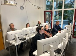 Sechs Personen sitzen in einem Raum jeweils vor eigenen Computern