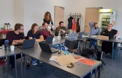 Auf dem Bild sind mehrere Menschen zu sehen, die auf Laptops gucken